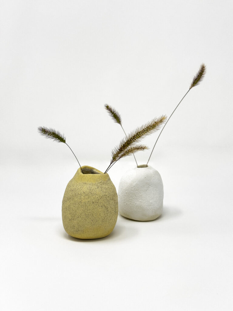 Two small, organic-shaped ceramic vases are displayed on a plain white background.